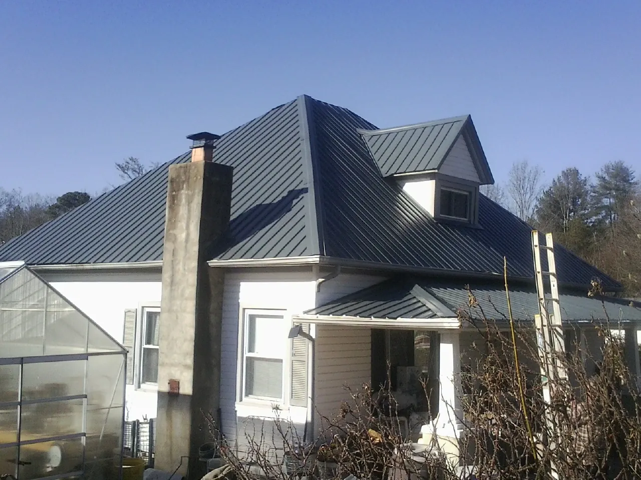 Dark blue standing seam metal roof on a white farmhouse with dormer — Slate & Tile Roof Repair by Roofing Brothers in Essex Fells