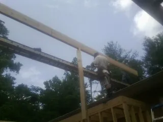Carpenter setting a ridge beam over a new addition frame — Ice Dam Removal by Roofing Brothers in Essex Fells