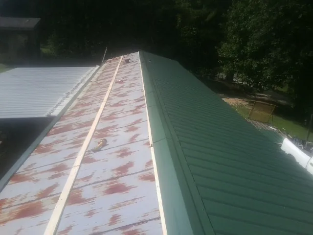 Old rusted panels beside newly installed green metal roofing — Wind Damage Roof Repair by Roofing Brothers in Essex Fells