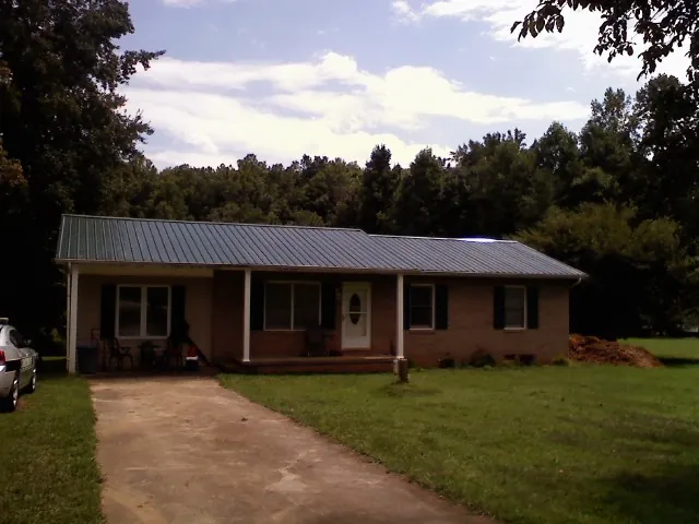 Dark green metal roof on a brick ranch with a covered porch in Essex Fells