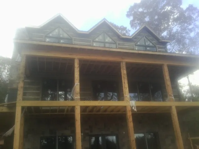 Dormers and porch framing on a large log home under construction — Roof Coating work by our crew in Essex Fells