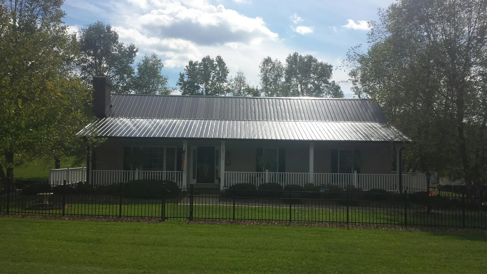 Gray metal roof on a brick ranch with a full width front porch — Gutter Guard Installation work by our crew in Essex Fells