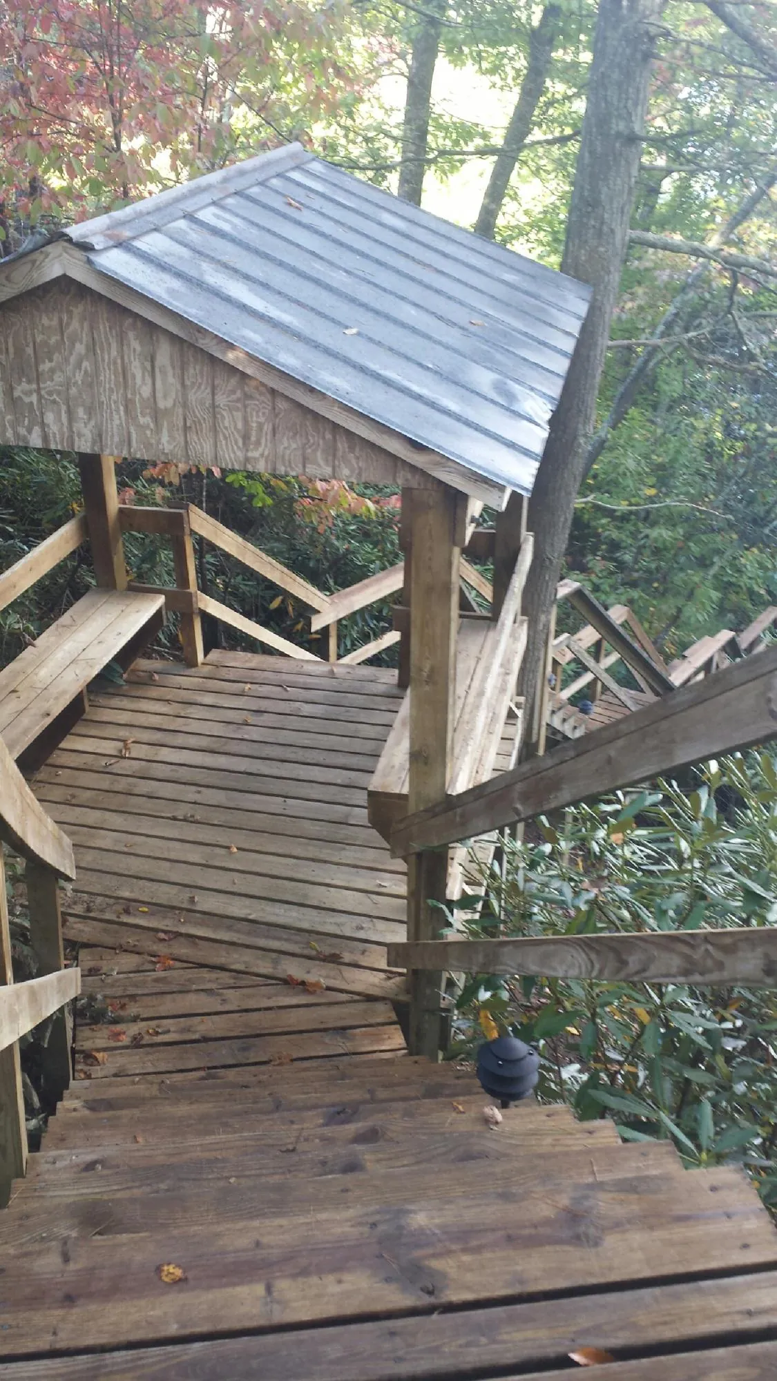 Metal roofed shelter over wooden steps on a wooded walkway — Skylight Repair & Installation work by our crew in Essex Fells