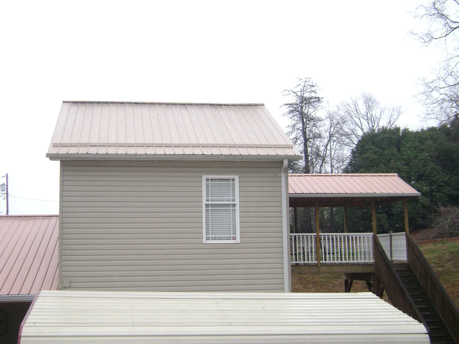 Tan metal roofs on a two story addition and attached porch, from a Roof Replacement job in Essex Fells
