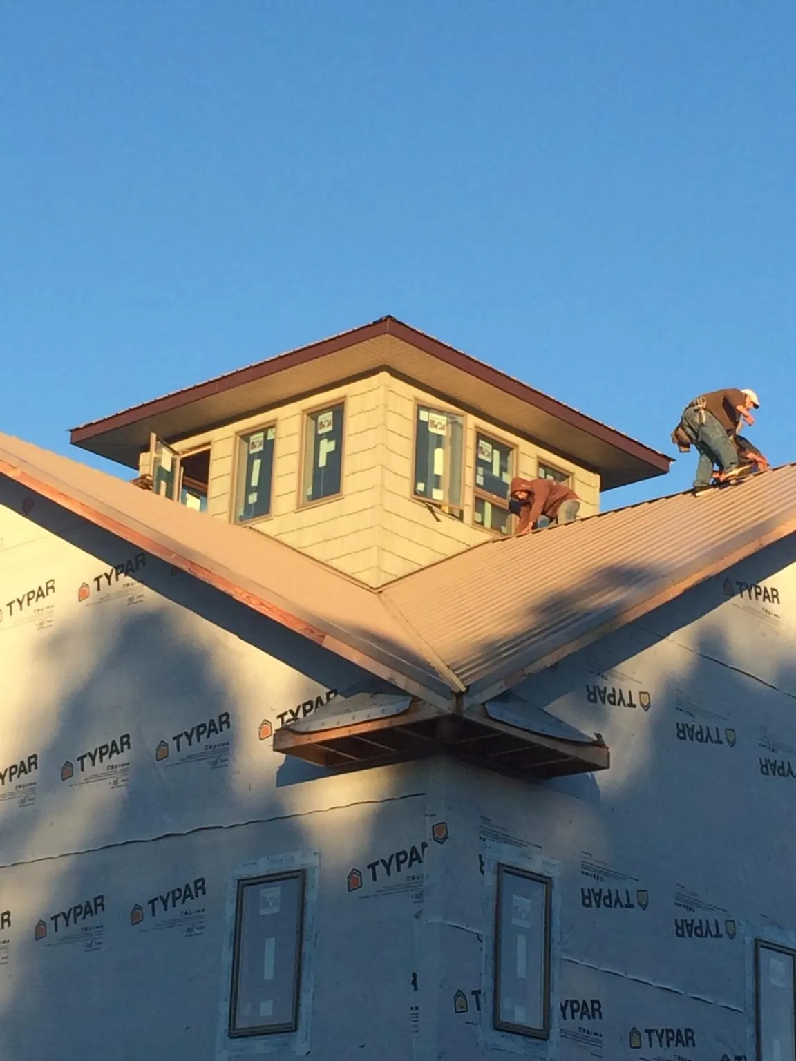 Roofers working around a rooftop cupola on a new metal roof at sunset — Roof Waterproofing in Essex Fells by Roofing Brothers